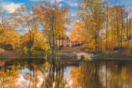 Calm lake with fall colors in the trees with home on the shoreline