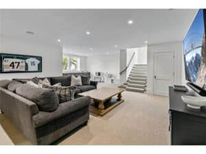 Streeter built lower level family room, television, flatscreen, sound bar, carpet, hockey jersey in display case, stairs at Lakeview Avenue Deephaven