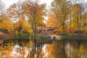 Calm lake with fall colors in the trees with home on the shoreline