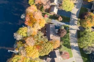 Aerial of home one lake with green yard on sunny day